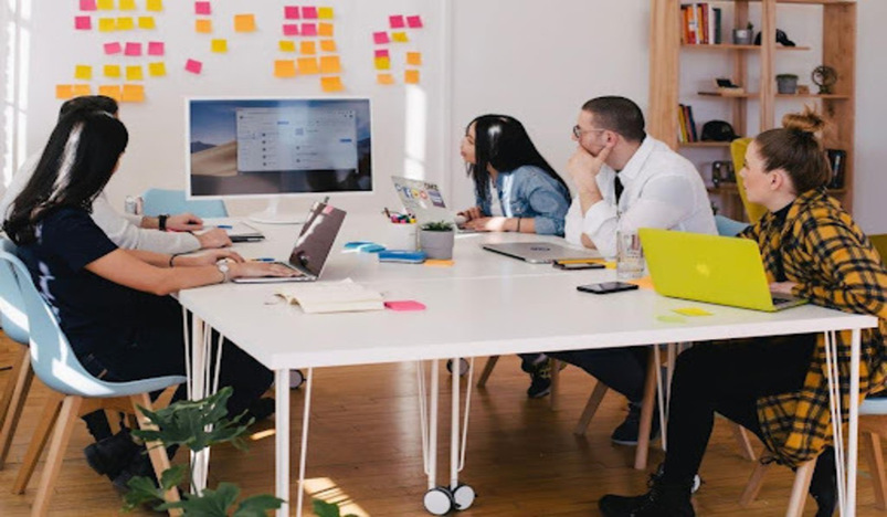 A team in an office discussing examples of a sales booking during a meeting